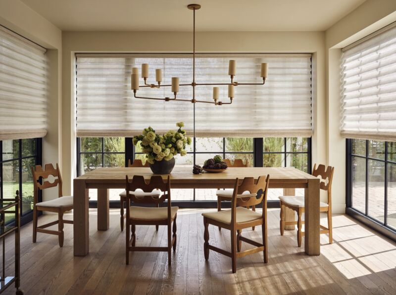 A dining room with soft, light-filtering Roman shades across wide windows