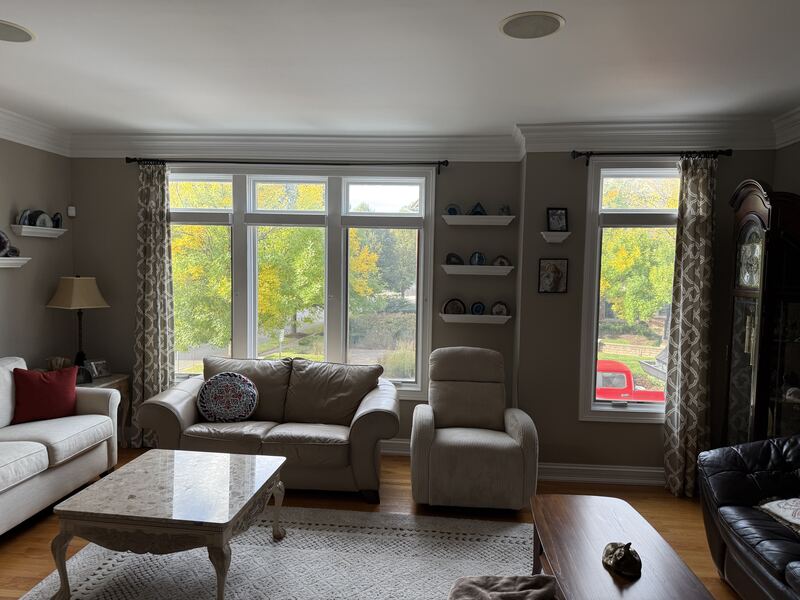 A living room with three tall bare windows before window treatments