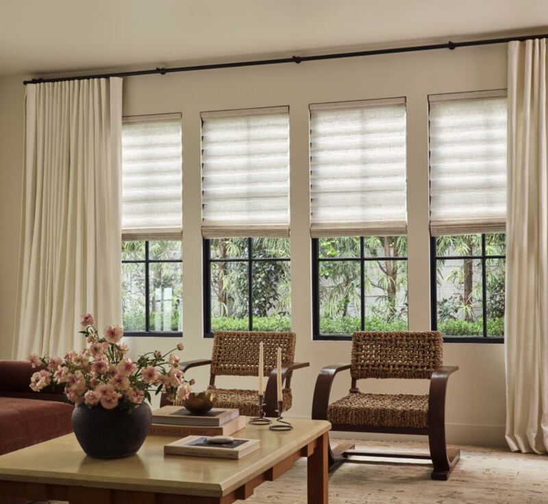 Roman shades layered under the panels the owners already had - considered, not crowded.